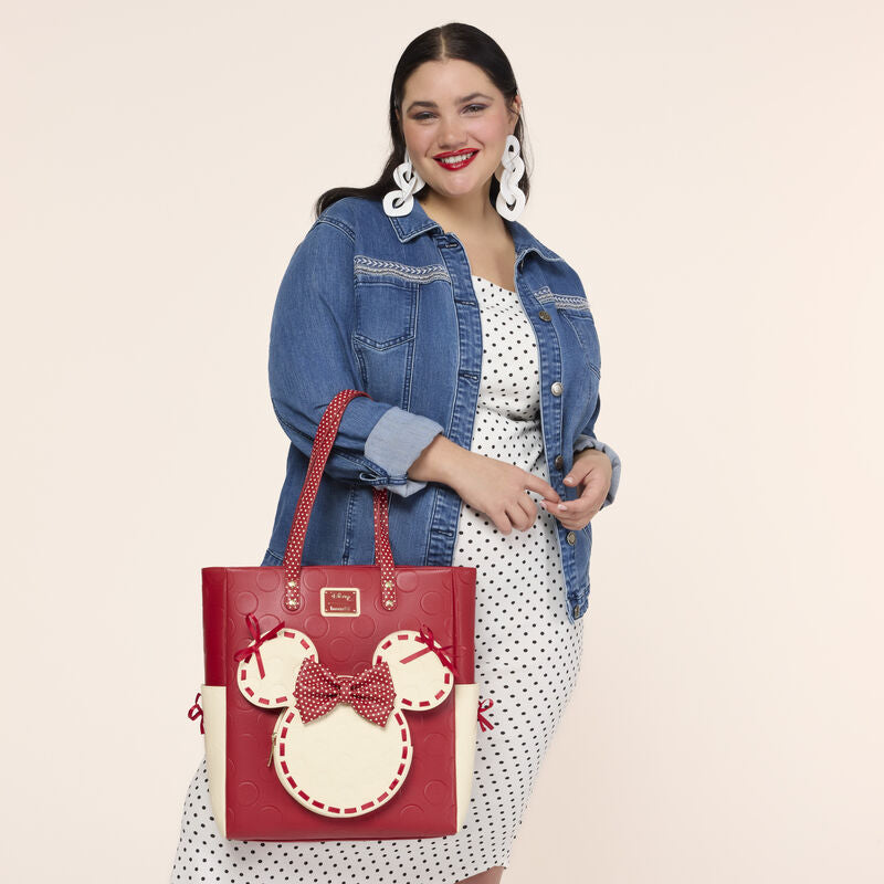 Woman holding a red handbag with a character design on a beige background