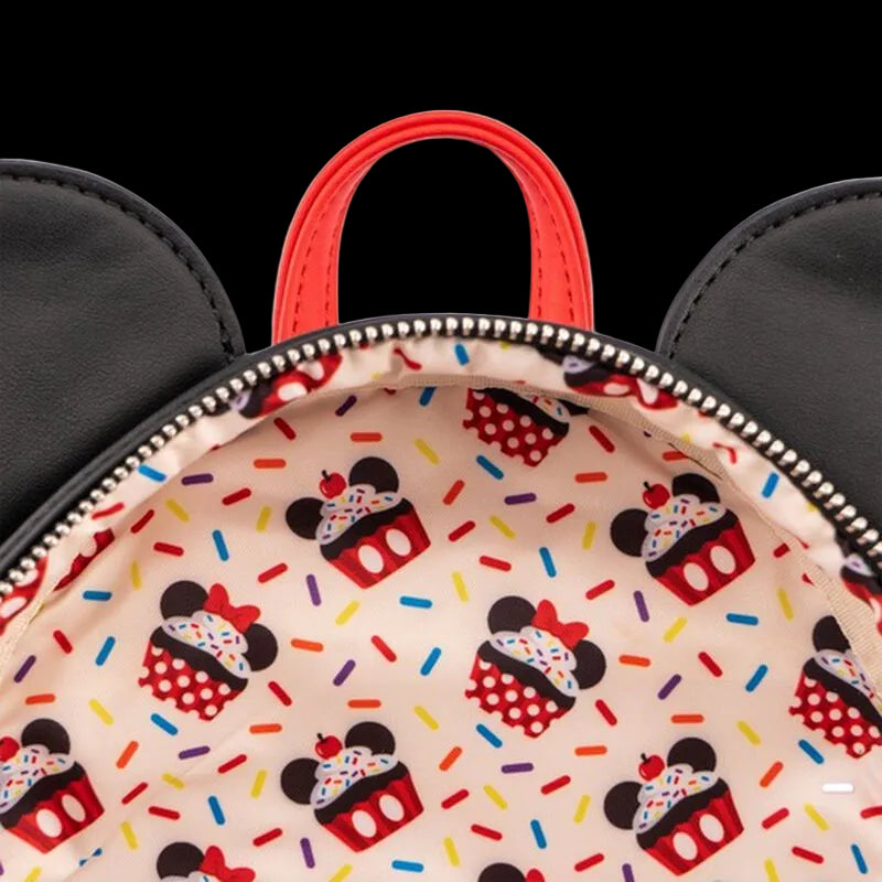 Close-up of a Mickey Mouse-inspired backpack with black ears, a red top handle, and a colorful cupcake print lining the interior.