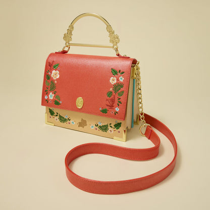 Red handbag with floral embroidery on a beige background