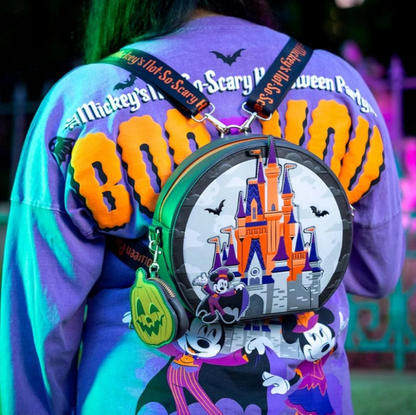 Person wearing a colorful jacket with 'Mickey's Not-So-Scary Halloween Party' text, holding a themed bag with castle design.