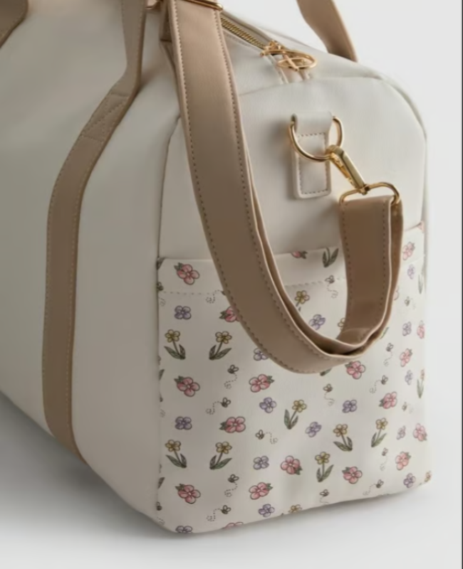 Floral-patterned handbag with beige handle and trim on a light background