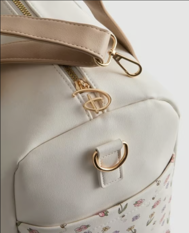 Close-up of a light gray backpack with floral pattern and gold accents on a white background