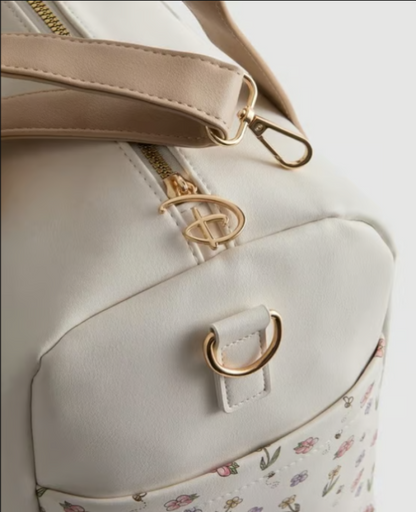 Close-up of a light gray backpack with floral pattern and gold accents on a white background
