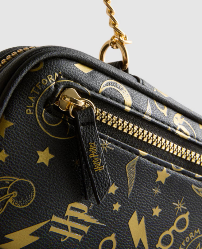 Black handbag with gold Harry Potter-themed patterns on a light gray background