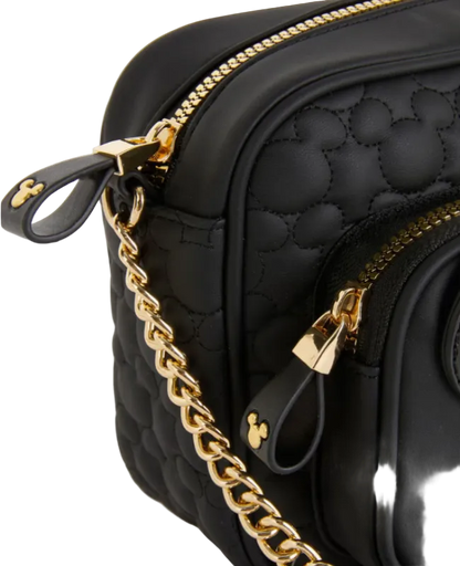 Black quilted handbag with gold chain and accents on a light gray background