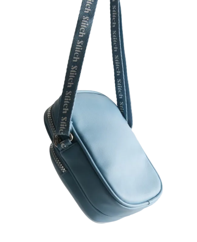 Light blue handbag with a matching strap on a light gray background