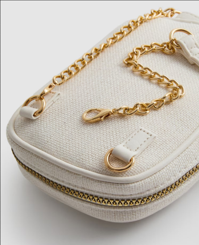 White handbag with gold chain strap and zipper on a light gray background