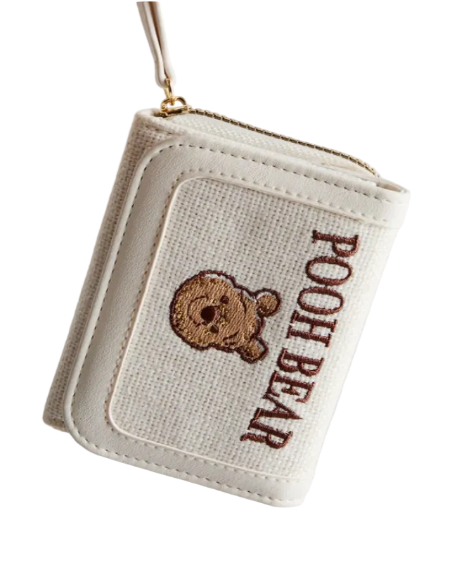 Small beige pouch with embroidered bear design and 'POOH BEAR' text on a light gray background