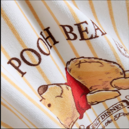 Close-up of fabric with 'Pooh Bear' text and a bear illustration on a striped background.