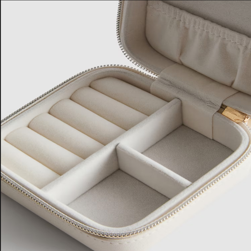Open beige jewelry box with compartments on a light background