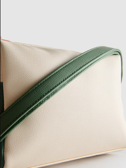 Beige clutch bag with green strap on a light gray background