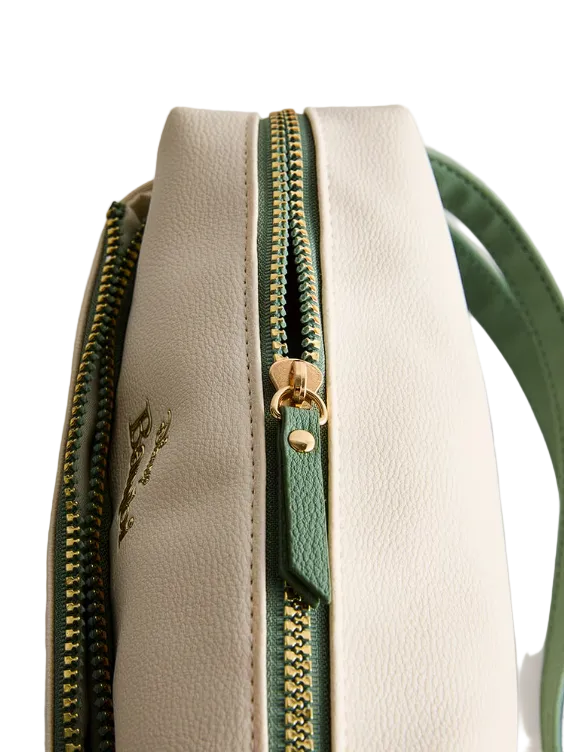 Close-up of a beige handbag with a green zipper on a light gray background