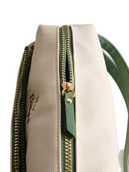 Close-up of a beige handbag with a green zipper on a light gray background