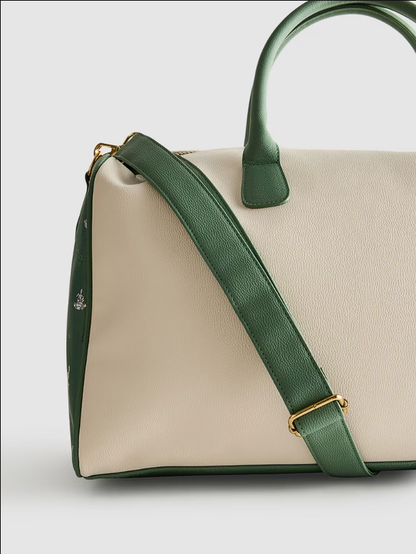 Green and beige handbag with a gold zipper on a light gray background