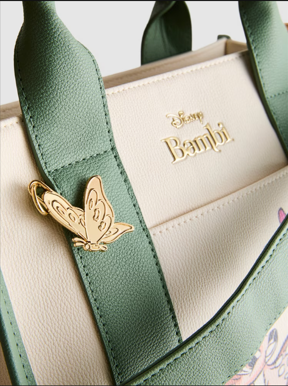 Green handbag with 'Bambi' branding and a gold butterfly pin on a white background