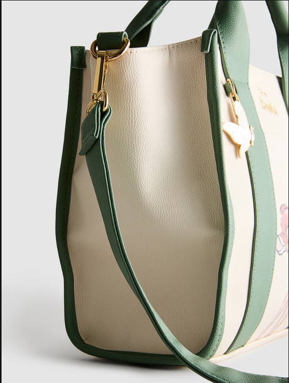 Beige handbag with green strap and trim on a light gray background
