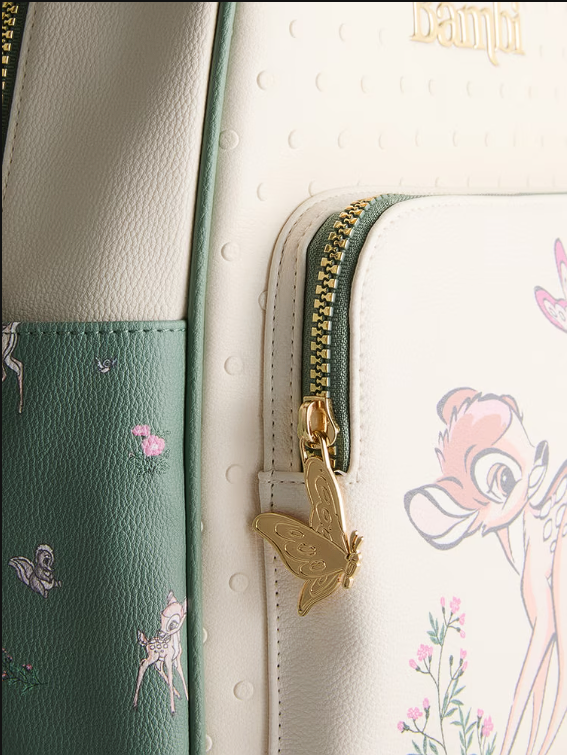 Close-up of a green and white bag with floral patterns and a gold zipper pull.