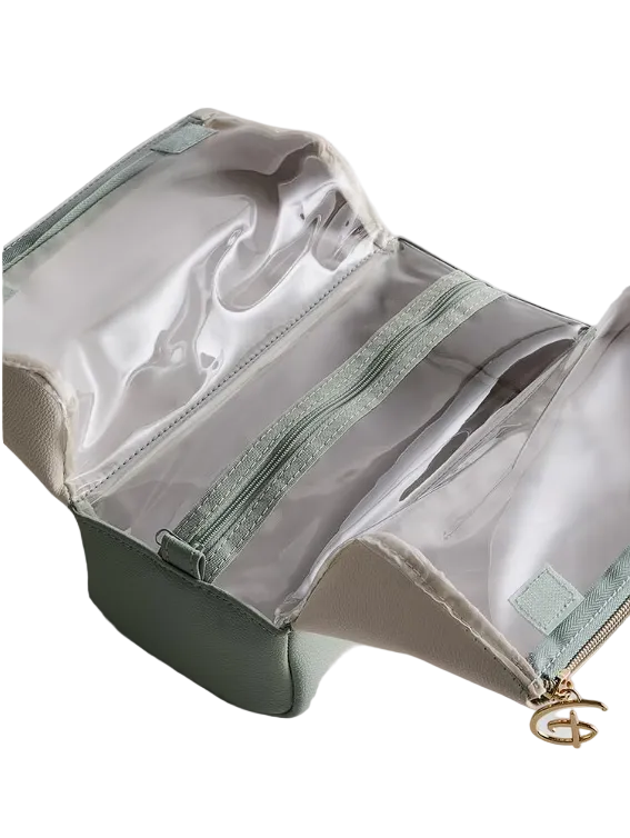 Green toiletry bag with clear compartments on a light gray background