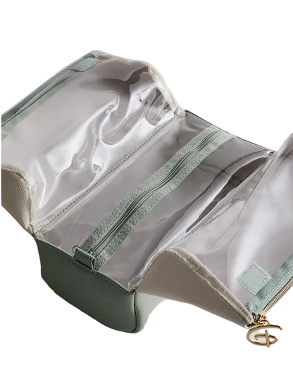 Green toiletry bag with clear compartments on a light gray background