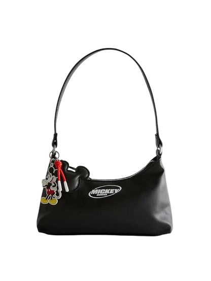 Black handbag with a Mickey Mouse charm on a light gray background