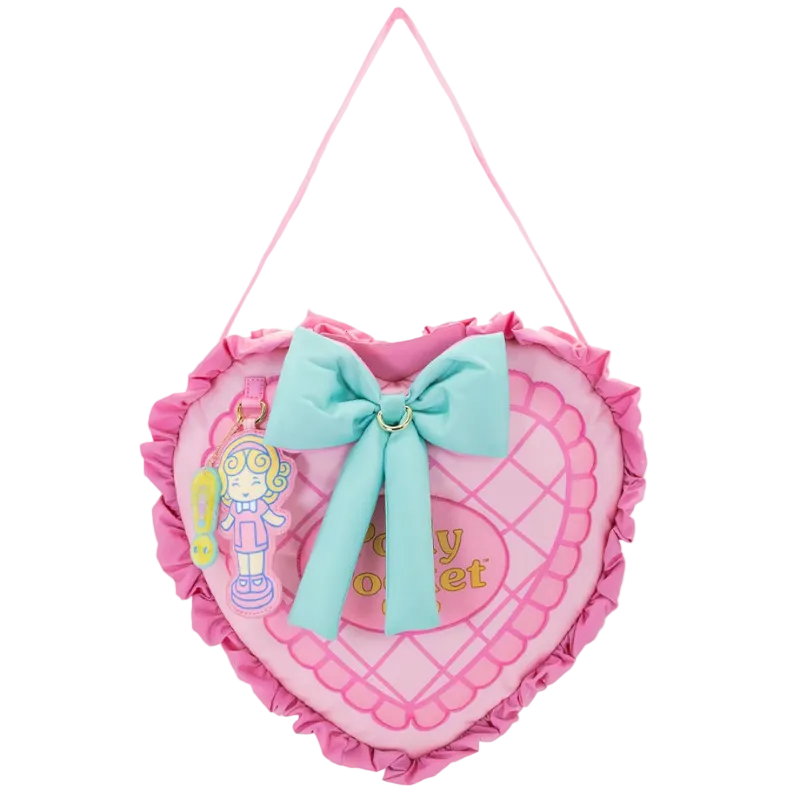 Heart-shaped pink pillow with a blue bow and toy figure on a white background