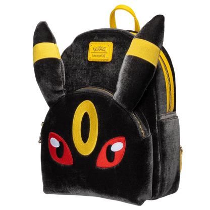 A black plush Pikachu-themed backpack with yellow ear bands, a yellow eye detail, red embroidered eyes, and gold zippers, shown on a plain white background.
