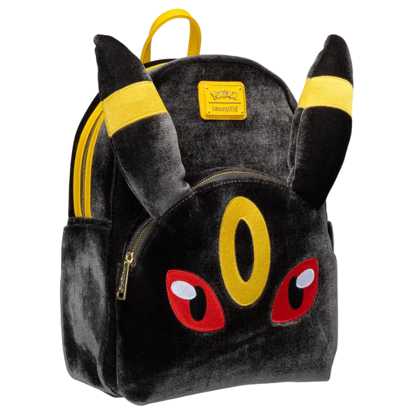 A plush toy backpack designed to look like the Pokémon character Eevee, featuring black plush fabric, yellow ear accents, red eyes, and a yellow front pouch, shown on a plain white background.