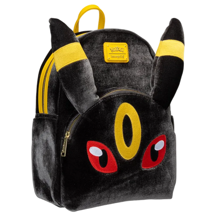 A plush toy backpack designed to look like the Pokémon character Eevee, featuring black plush fabric, yellow ear accents, red eyes, and a yellow front pouch, shown on a plain white background.
