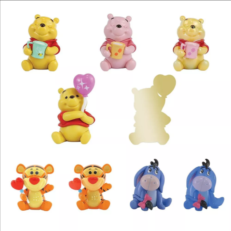 A set of Disney Winnie the Pooh character figurines and accessories on a plain white background, including Pooh holding a blue cup, Piglet holding a yellow cup, Winnie the Pooh holding a pink cup, Winnie the Pooh holding a purple balloon, a gold bear-shaped mirror, and Tigger and Eeyore figures.