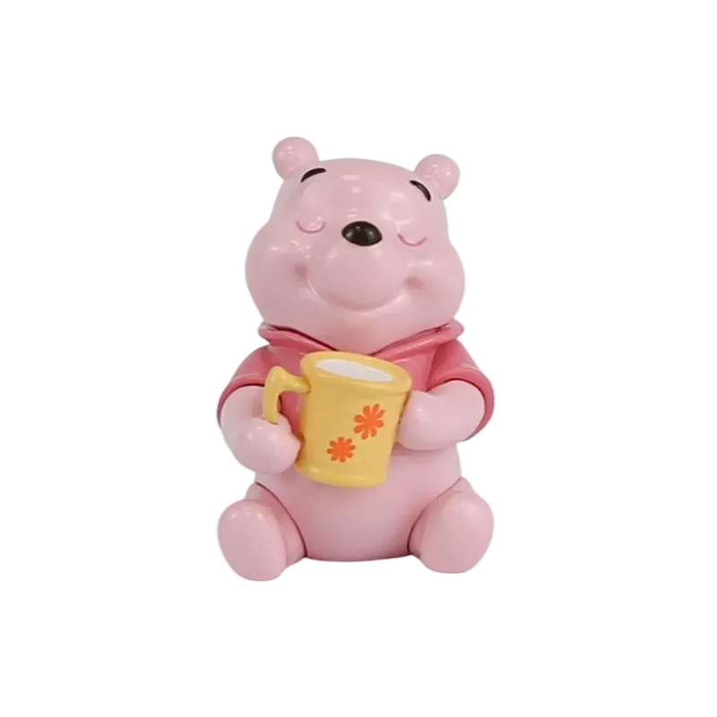 A pink Winnie the Pooh bear figurine holding a yellow mug with orange flower details, set against a plain white background.
