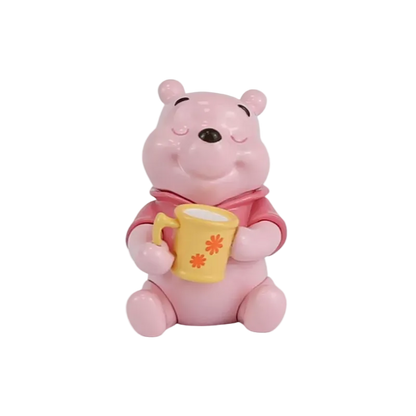 A pink Winnie the Pooh bear figurine holding a yellow mug with orange flower details, set against a plain white background.