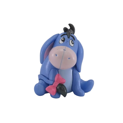 A small blue cartoon donkey figurine with a pink snout, black hair tuft, and pink bow, shown on a plain white background.