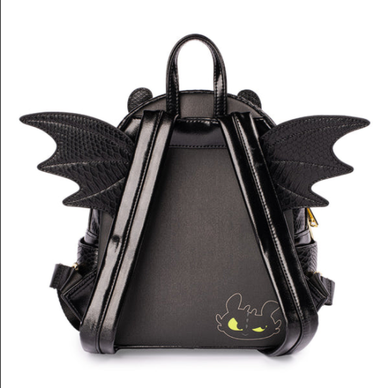 A black faux-leather mini backpack designed like Toothless from How to Train Your Dragon, featuring textured wings on the back, dual top handles, and a small Toothless face graphic on the lower front, shown against a plain white background.
