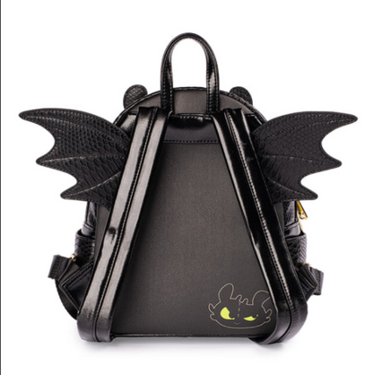 A black faux-leather mini backpack designed like Toothless from How to Train Your Dragon, featuring textured wings on the back, dual top handles, and a small Toothless face graphic on the lower front, shown against a plain white background.