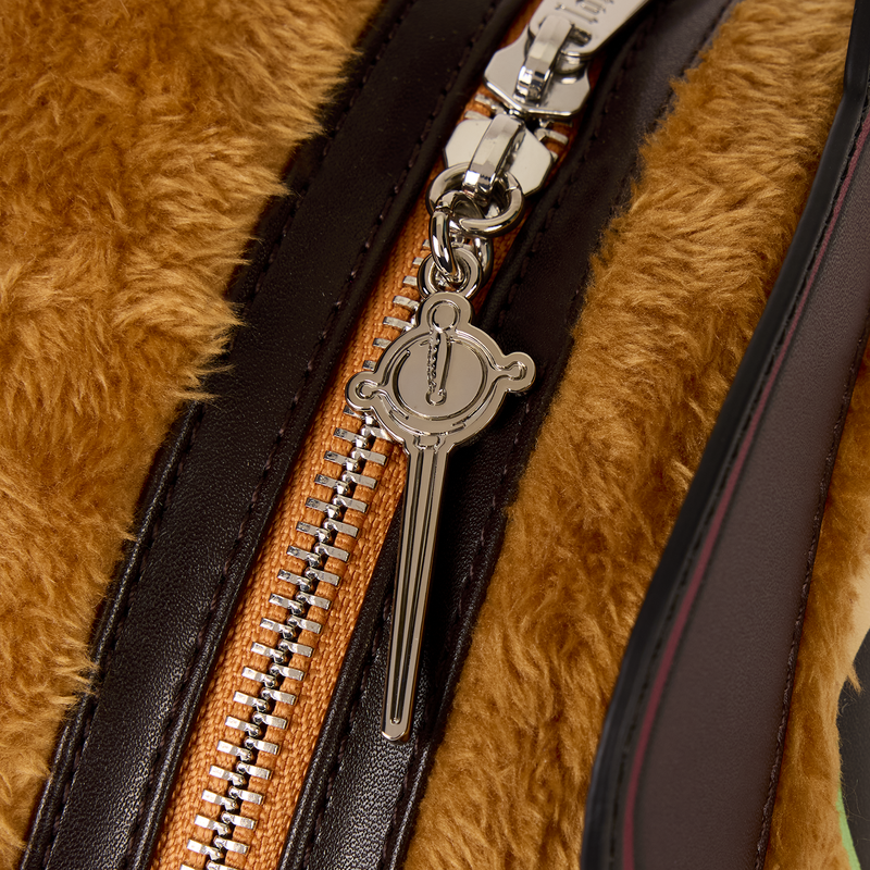 Close-up of a zipper on a fur-textured surface with a decorative pull.