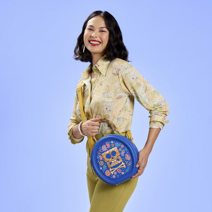 Woman holding a blue circular bag with floral design against a light blue background