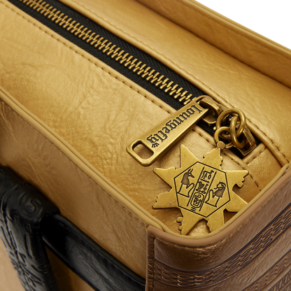 Close-up of a tan leather suitcase with a gold zipper pull featuring a star design.