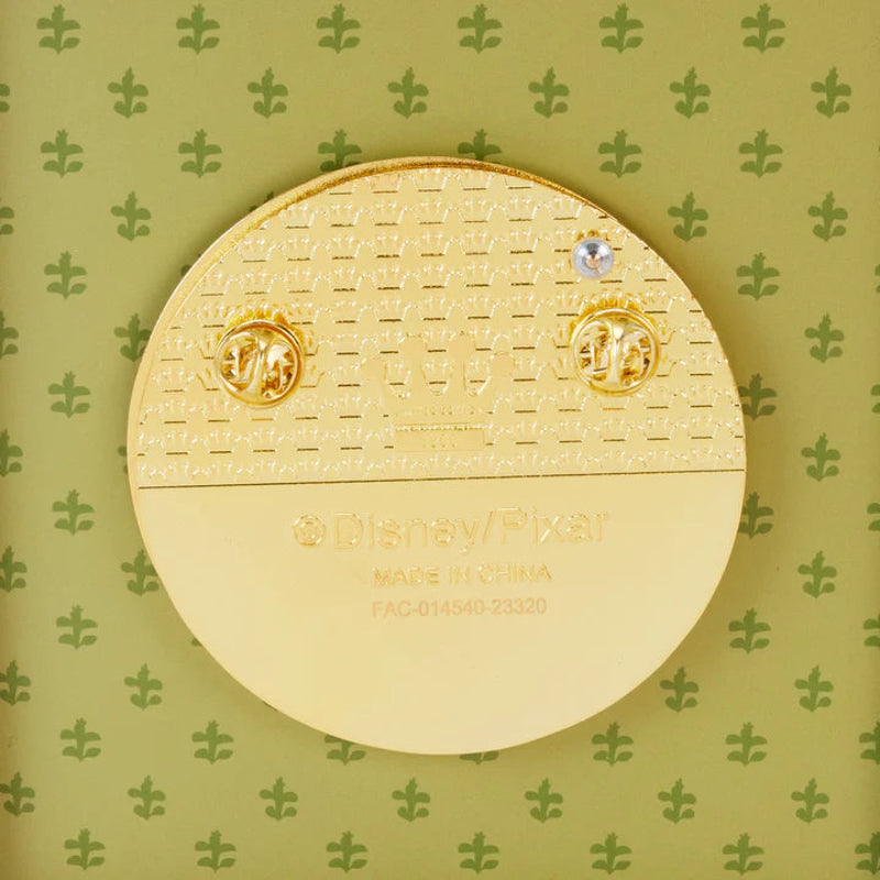 Gold earring set in a round gold case on a green floral patterned background