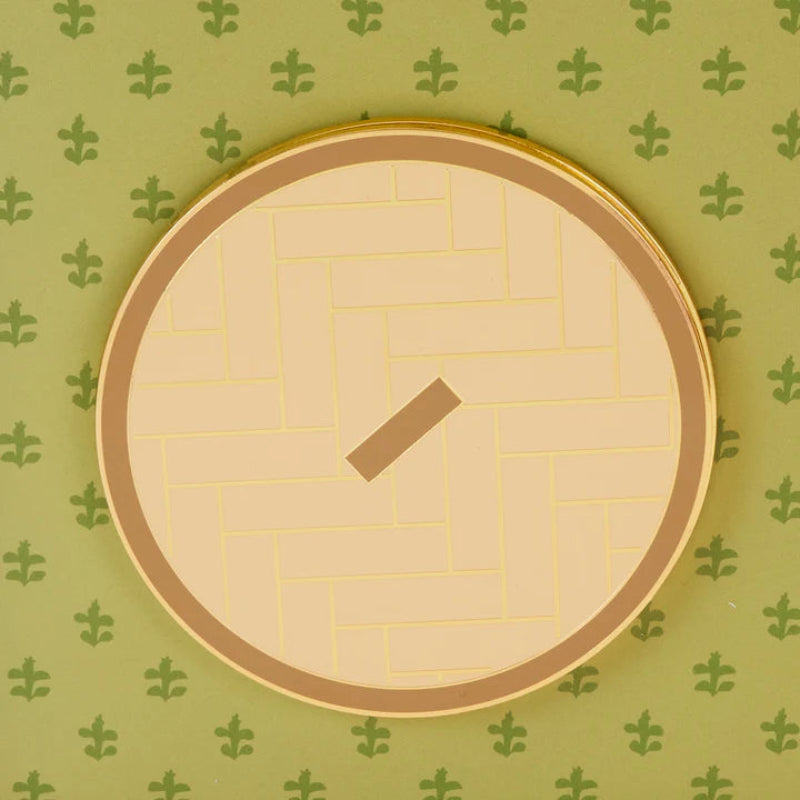 Circular clock with gold rim and beige face on a green patterned background