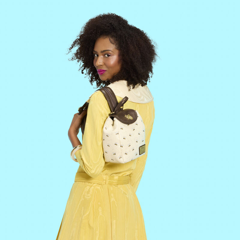 Woman in a yellow dress holding a white backpack with brown accents against a light blue background