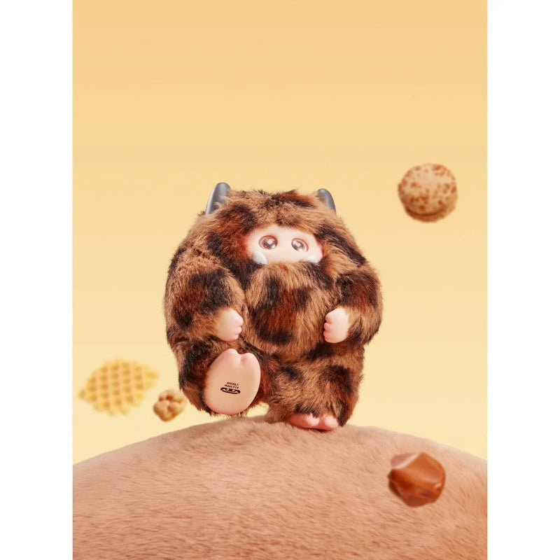 Plush toy resembling a cartoon character with a brown and black pattern, sitting on a person's shoulder against a yellow background.