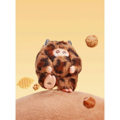 Plush toy resembling a cartoon character with a brown and black pattern, sitting on a person's shoulder against a yellow background.