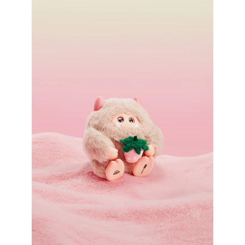 Plush toy resembling a monkey holding a green leaf on a pink background