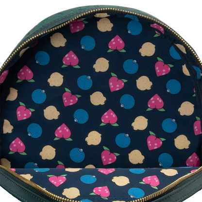 Close-up of the interior of a green backpack showing a navy blue fabric lining with a colorful pattern of pink strawberries, blue blueberries, and beige lemons, finished with gold-tone zippers.
