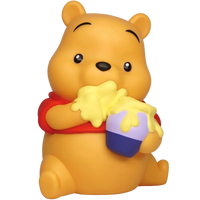 A Winnie the Pooh bear figurine or bath toy in a sitting pose, holding a honey pot with yellow honey dripping over it. The bear is yellow with a red shirt, and the pot is purple and blue, set against a plain white background.