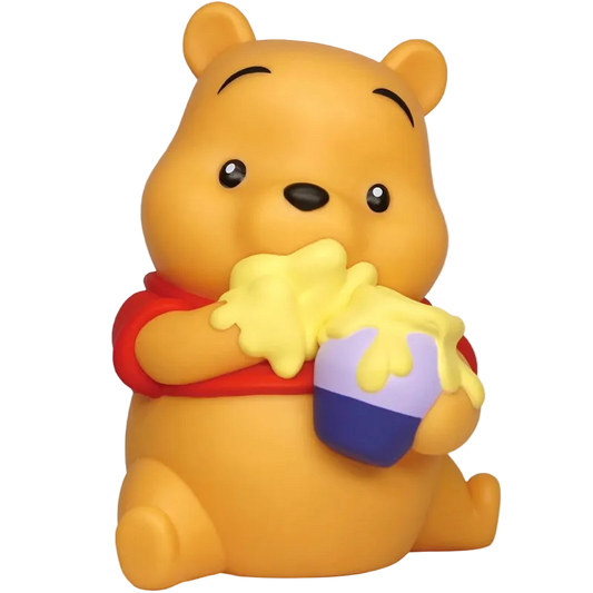 A Winnie the Pooh bear figurine or bath toy in a sitting pose, holding a honey pot with yellow honey dripping over it. The bear is yellow with a red shirt, and the pot is purple and blue, set against a plain white background.