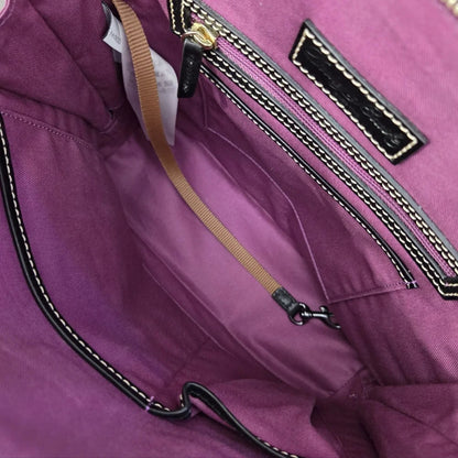 Close-up of the interior of a purple nylon bag, showing a zippered pocket with black and gold trim, a tan webbing strap, and a white product tag.
