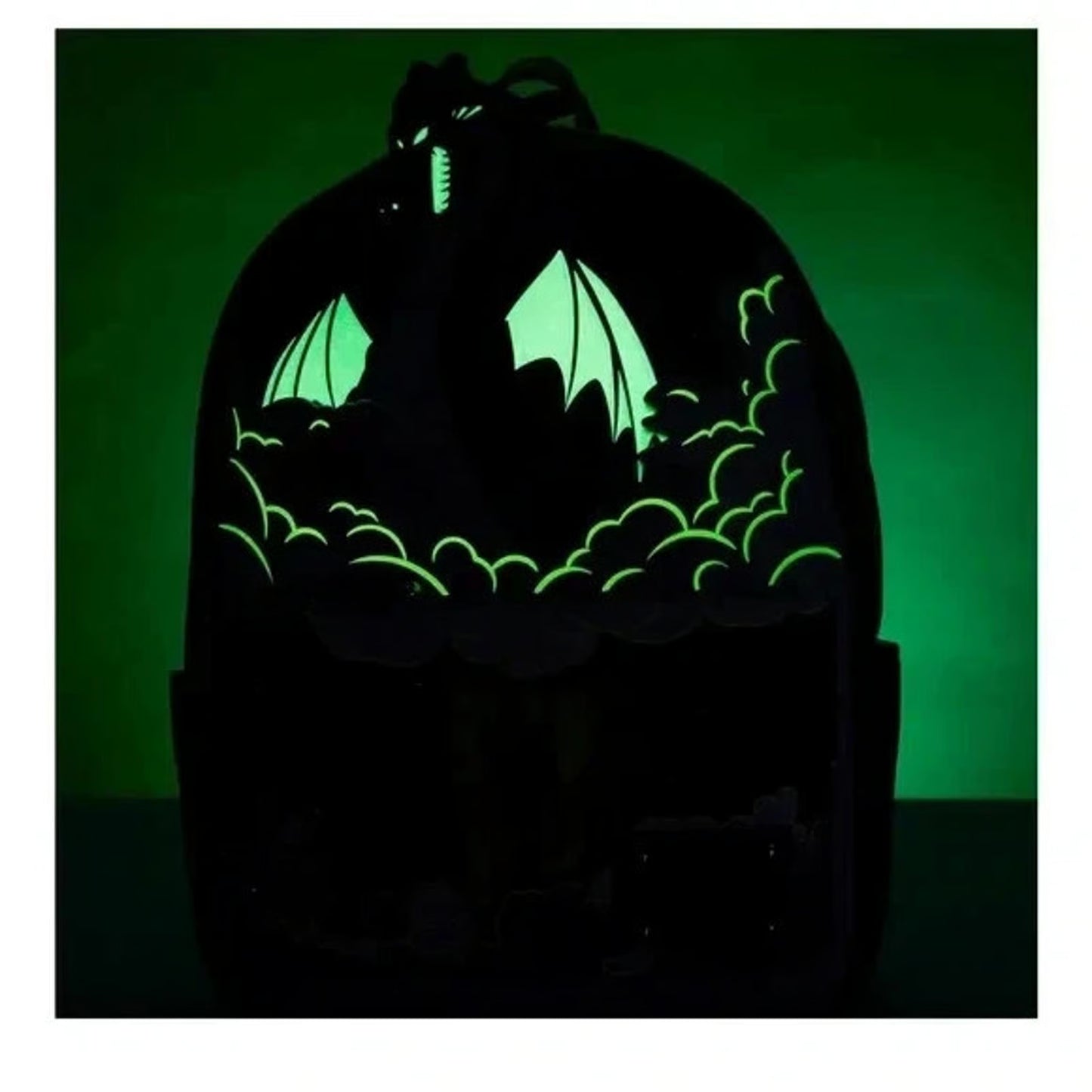 Glowing dragon silhouette in a dark enclosure with a green light on a black background