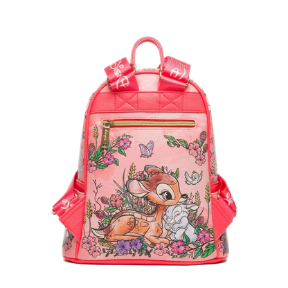 A pink faux-leather backpack featuring a Bambi illustration with flowers, butterflies, and a deer, accented with red straps and gold zippers.