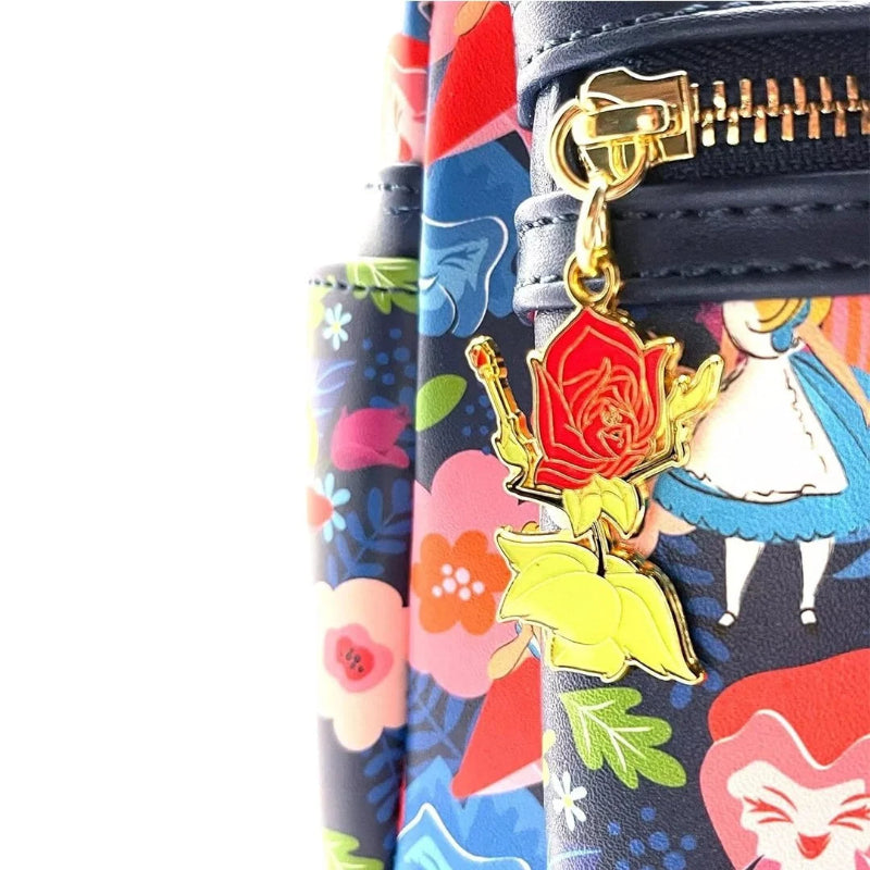 Close-up of a colorful patterned clutch or wallet with a black zipper and a gold-tone charm shaped like a red rose with yellow leaves, shown against a white background.